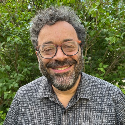 Man smiling in front of nature background.