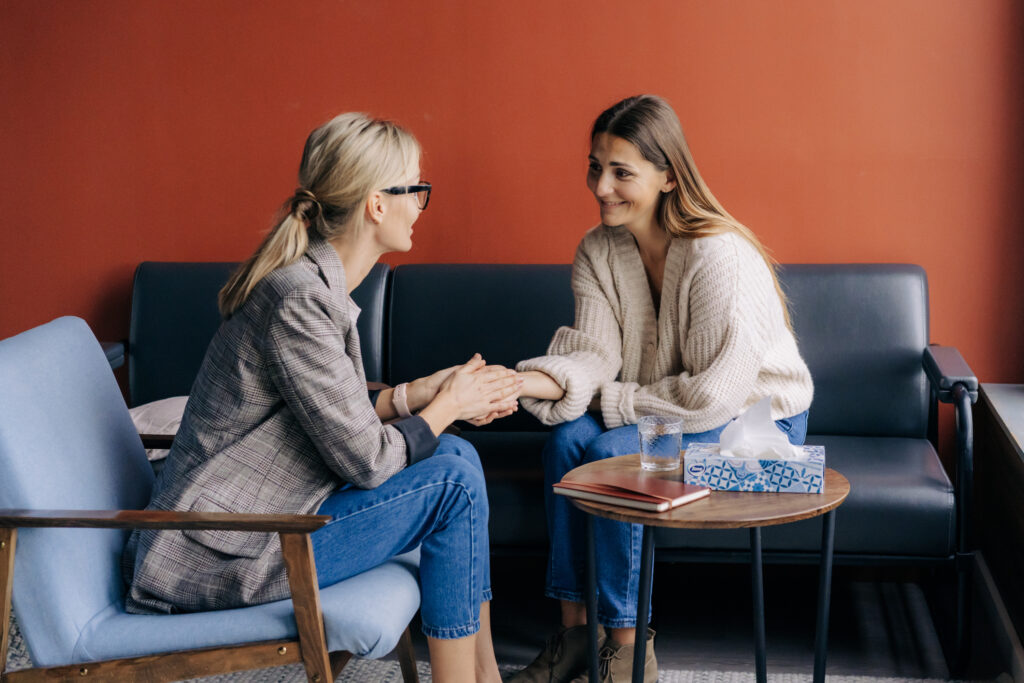 Empathic female financial counselor holding female client's hand giving professional support