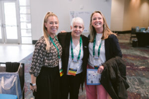Three women stand together for a photo at Symposium.