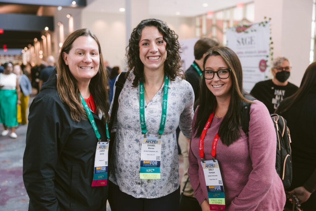 Three white women smiling in the hallway of Symposium.