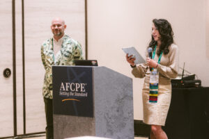 Man and woman stand at the podium at AFCPE Symposium
