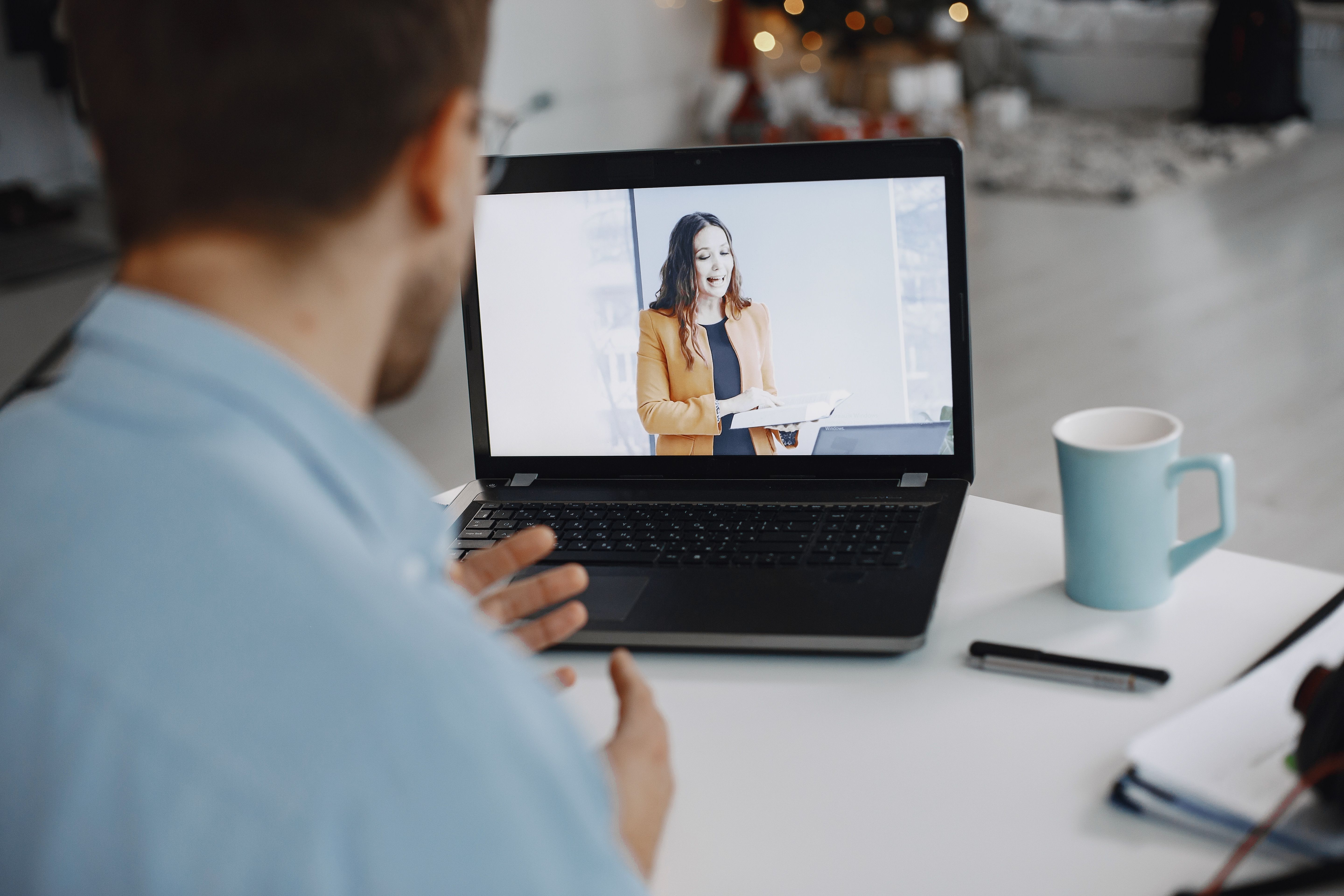 white man taking part in an online class led by a white woman on the laptop screen