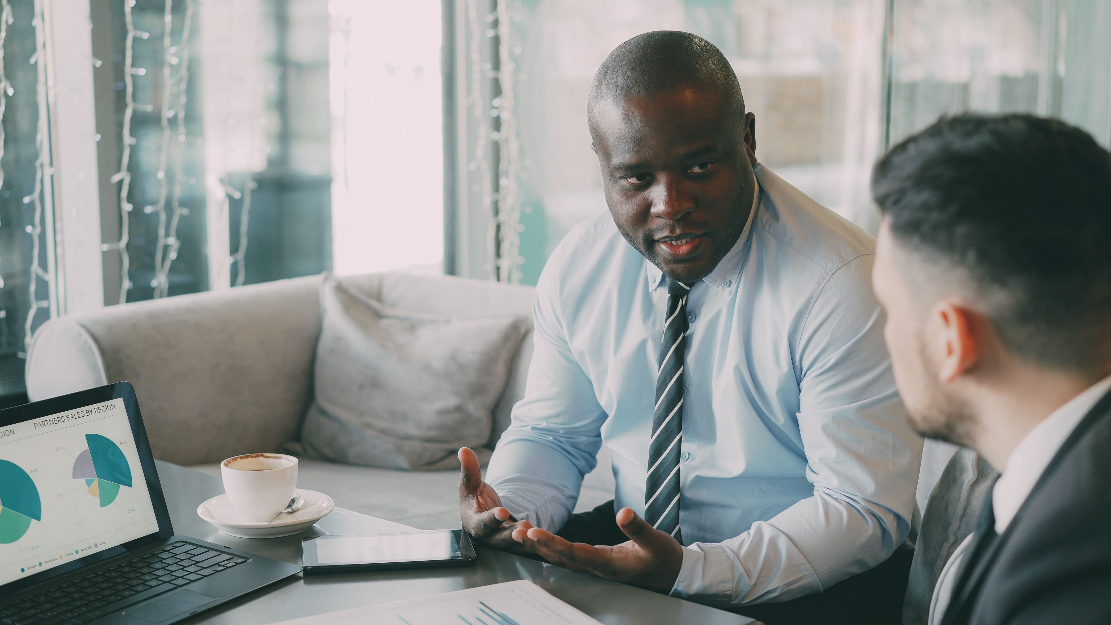 black male financial advisor in a button down shirt and tie meeting with a client
