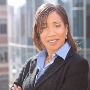 Photo of a woman in a blue shirt and black sweater. 
