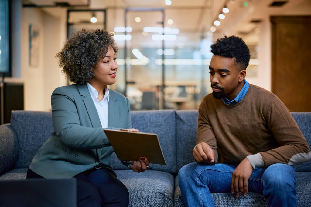 Black woman financial advisor consulting African American man while going through paperwork on a meeting in the office.