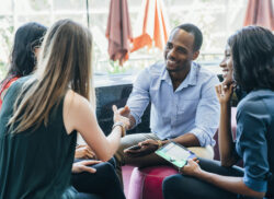 Business meeting in lobby of colorful modern office space. A black man shakes hands with a white woman smiling