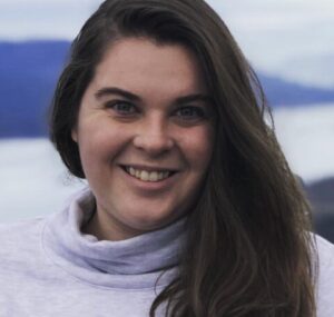 white woman with long brown hair wearing a bulky grey turtleneck