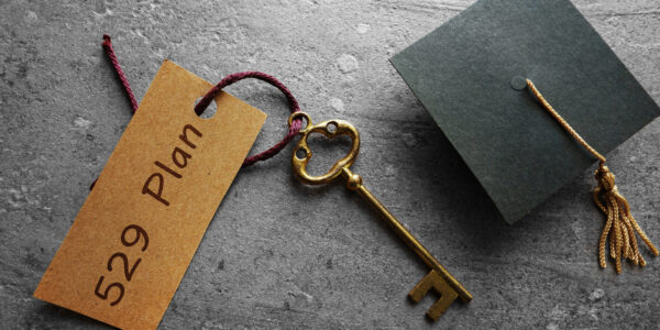 Gold key with 529 Plan tag and mini graduation cap -- college savings concept