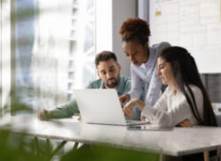 black woman teaching a white man and white woman on a laptop