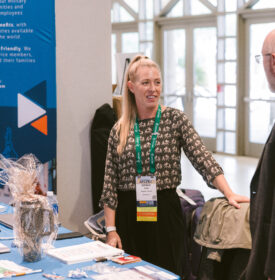Woman exhibiting at Symposium talking to a man
