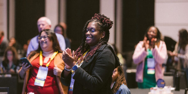 Symposium attendees standing and applauding after a presentation