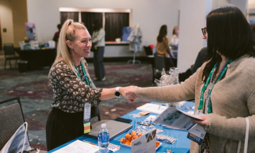 Attendee and exhibitor shaking hands at Symposium