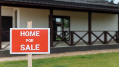 Red and white Home for Sale sign in front of a property