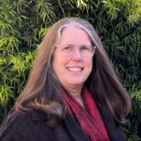 headshot of a woman with greenery in the background